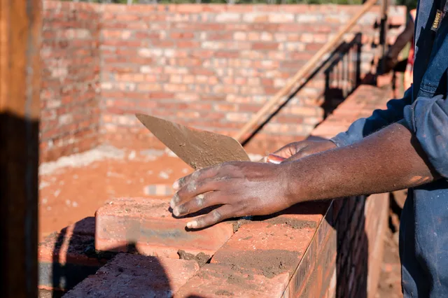 Laying bricks by hand, course by course